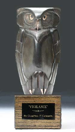A photo of the limited edition bronze owl, Vigilance, by Clarence Cameron. It has a dark brown patina with bronze highlights and it mounted on an oak base with a brass name plaque.